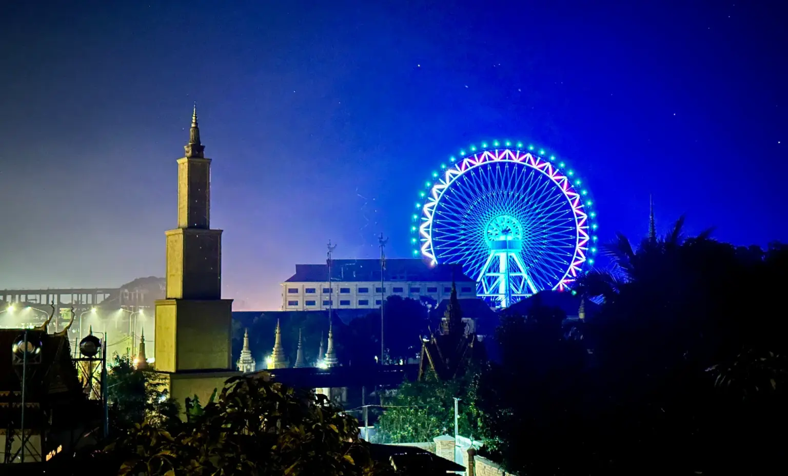 Night photo of the colorfully lit ferris wheel called the Angkor Eye in Siem Reap, picture taken at Saralya House.