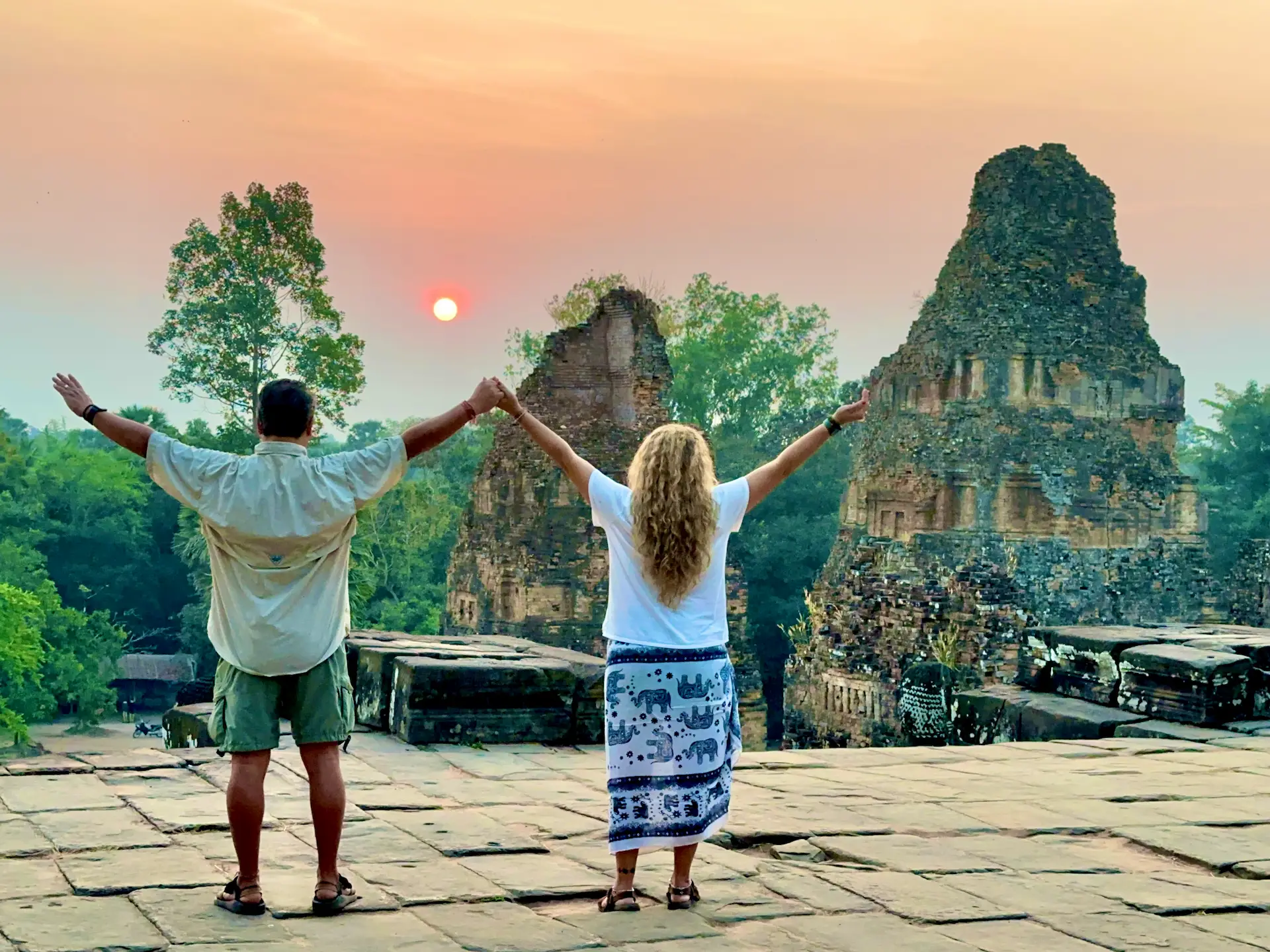 A wide angle shot of two people from the top of a temple as the sun rises
